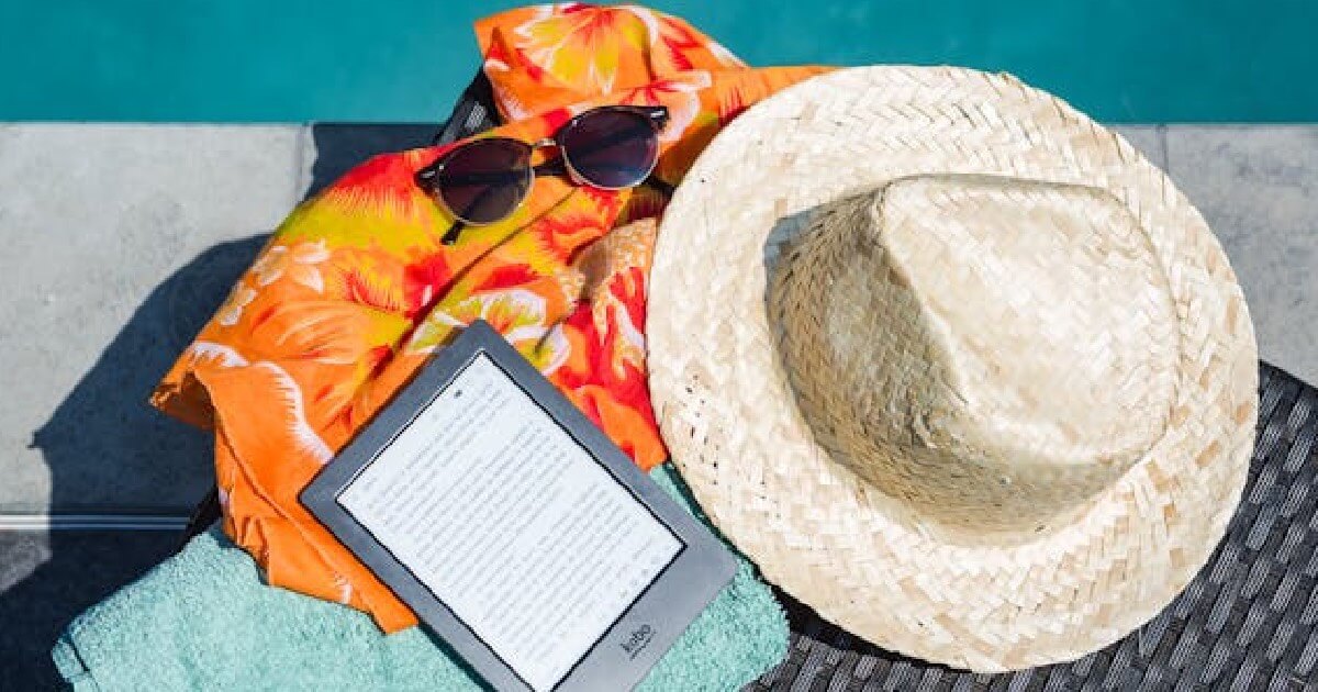 A Kindle e-reader placed on a colorful beach towel, perfect for summer reading by the ocean.
